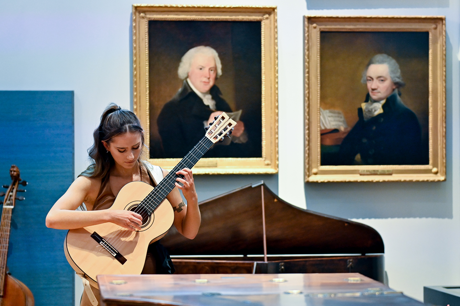 A guitarist performs in the H漫画 Museum in front of paintings and historical instruments